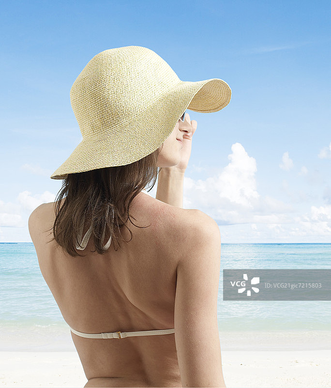 年轻女子在海滩上戴着遮阳帽图片素材