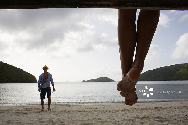 中年男人站在沙滩上，前景是女人的腿，美国维尔京群岛圣约翰图片素材