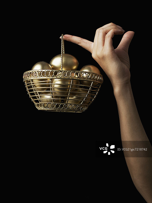 手指悬挂的金色鸡蛋篮图片素材