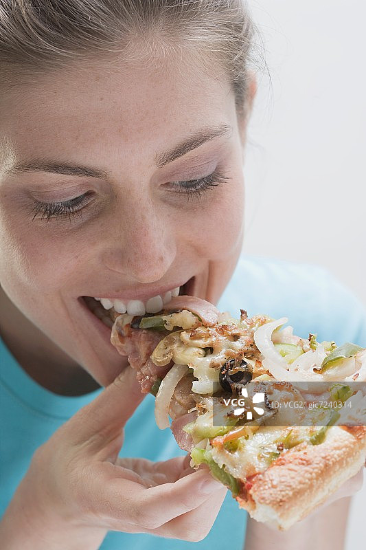 年轻女人吃一片蔬菜披萨图片素材