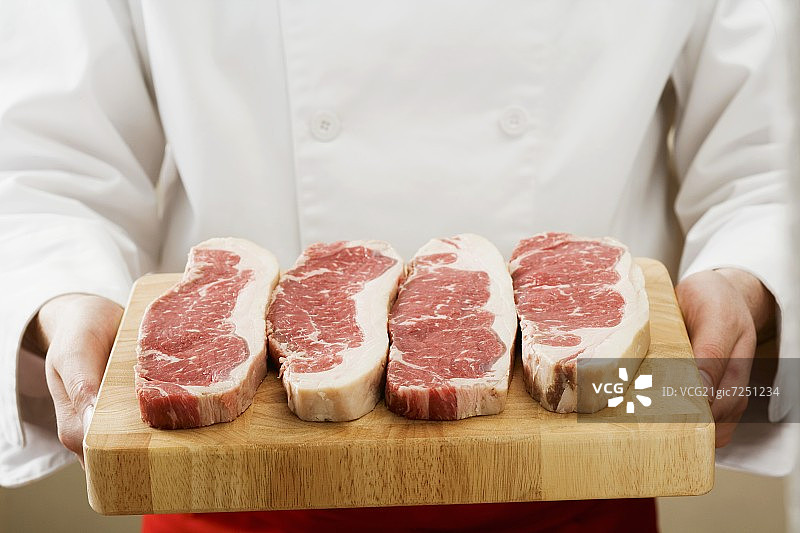 厨师在砧板上拿着西冷牛排图片素材