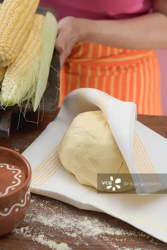 玉米饼面团和玉米棒，背景中的女人图片素材