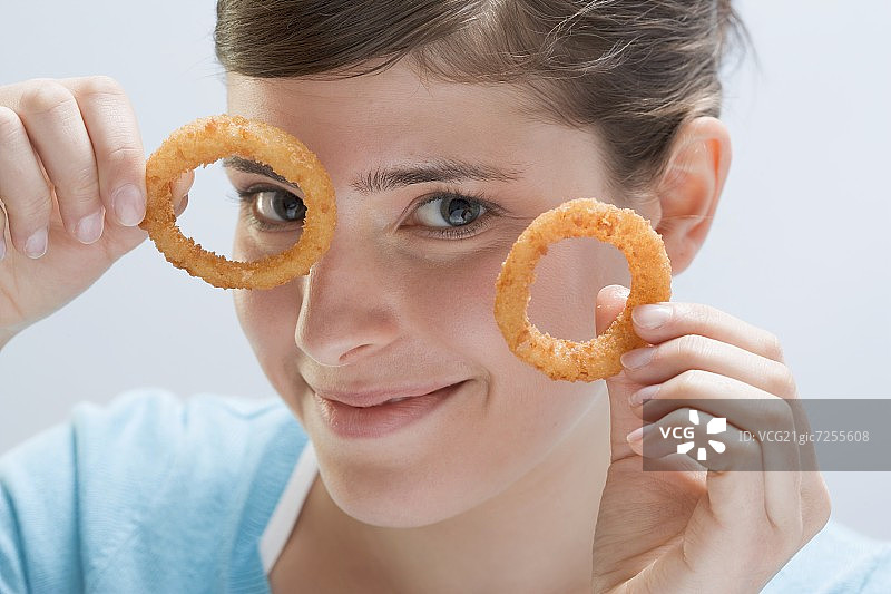 年轻女子举起两个炸洋葱圈图片素材