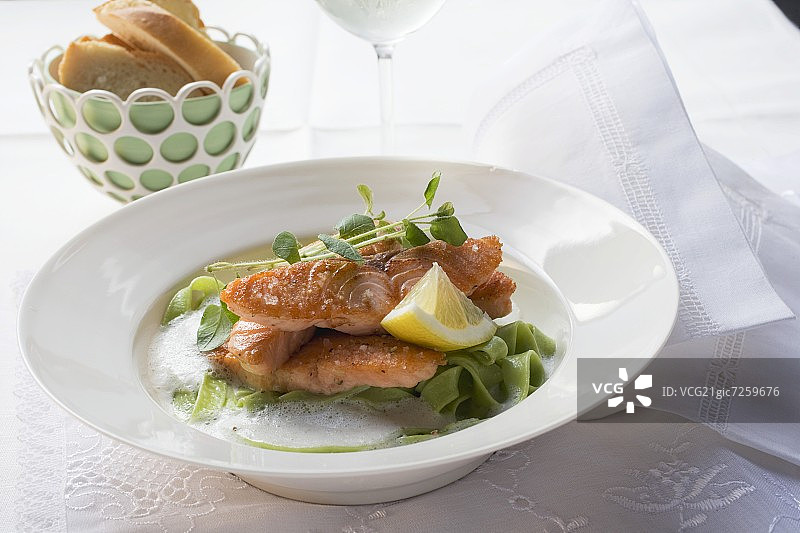 绿色带状意大利面上的三文鱼片图片素材