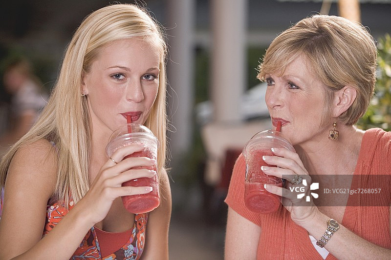 年轻女人和中年妇女喝冷冻草莓冰沙图片素材