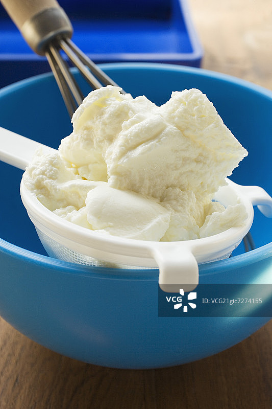 蓝Mixing碗中带搅拌器的筛子里的夸克乳酪图片素材