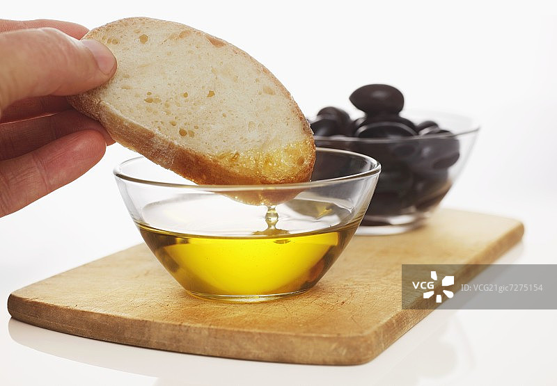 手拿白面包片蘸橄榄油图片素材