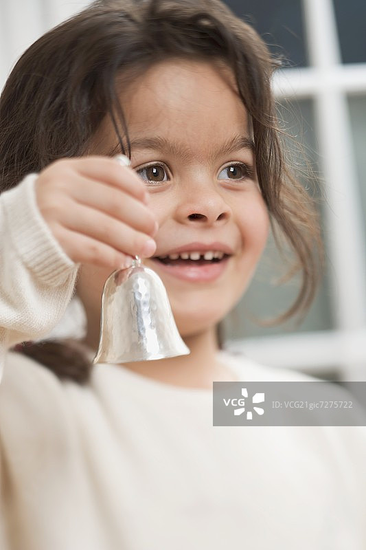 手持圣诞铃铛的小女孩图片素材