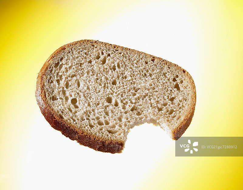 咬了一口的面包切片（黄色背景）图片素材