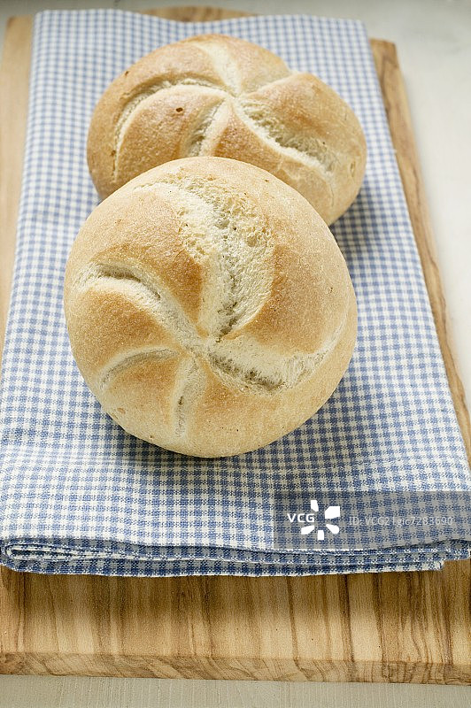 蓝白格子布上的两个面包卷图片素材