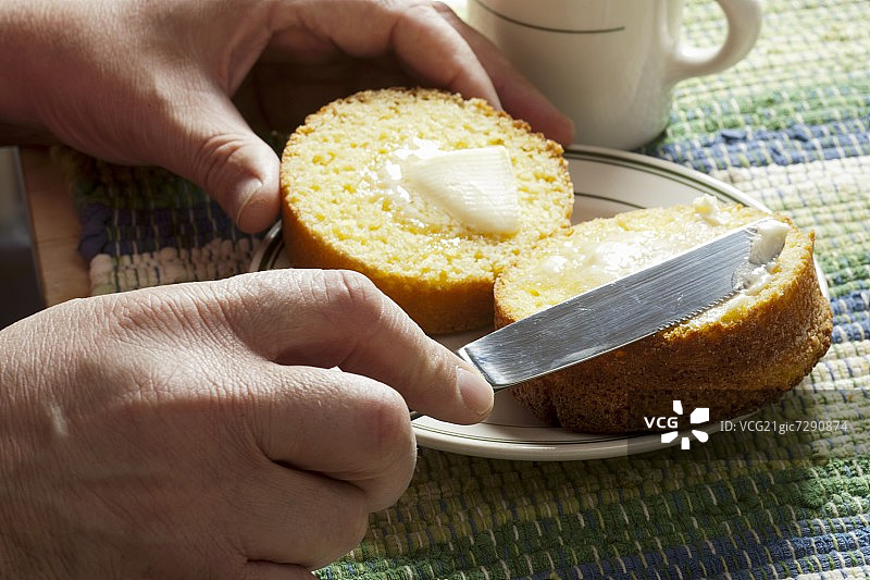 男子在涂抹对半切开的玉米松饼图片素材