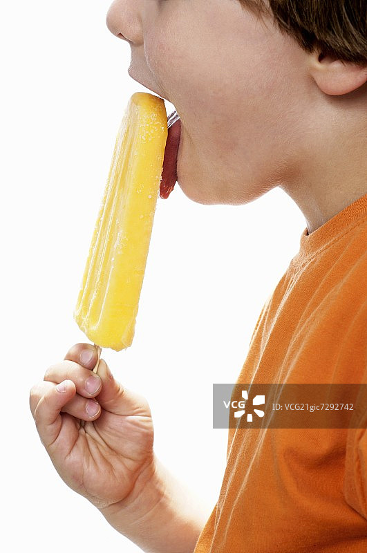 男孩快乐地吃着橙色冰棒图片素材