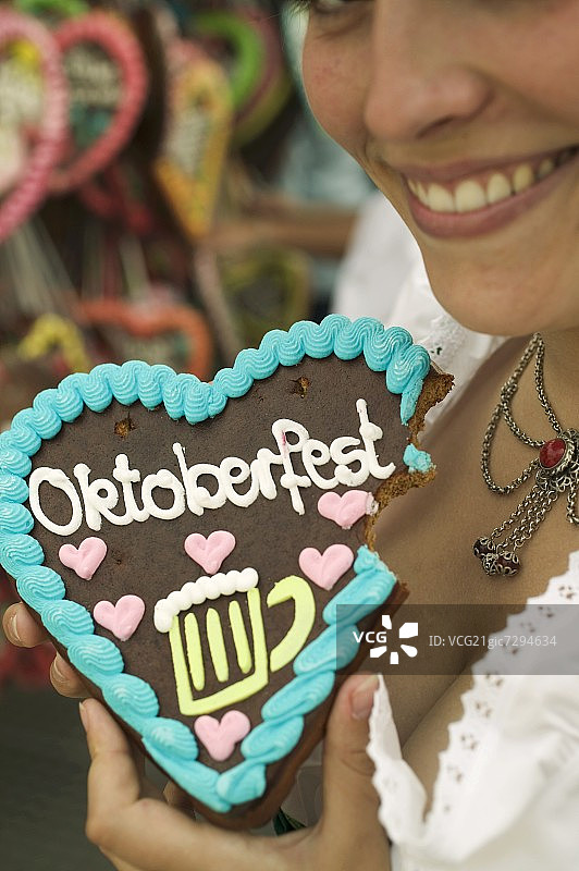 在慕尼黑啤酒节上，女人手拿咬了一口的姜饼心图片素材