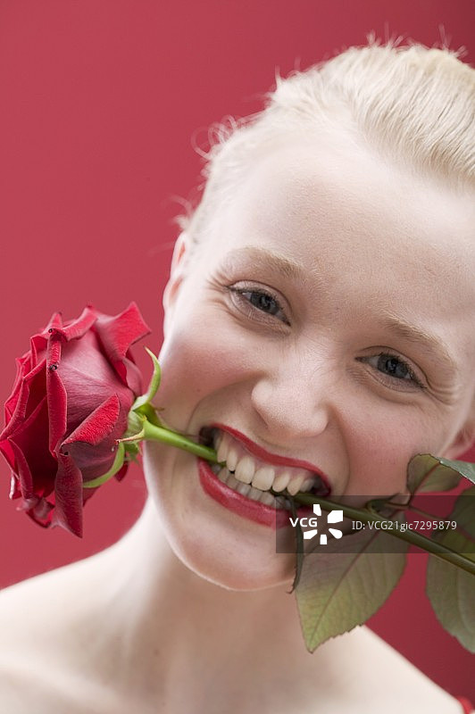嘴里叼着红玫瑰的年轻女人图片素材