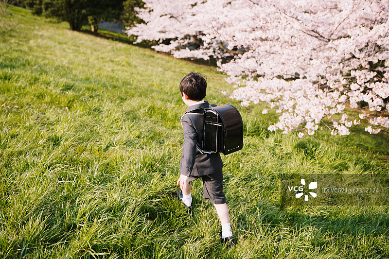 穿着校服走在草地上的小男孩图片素材