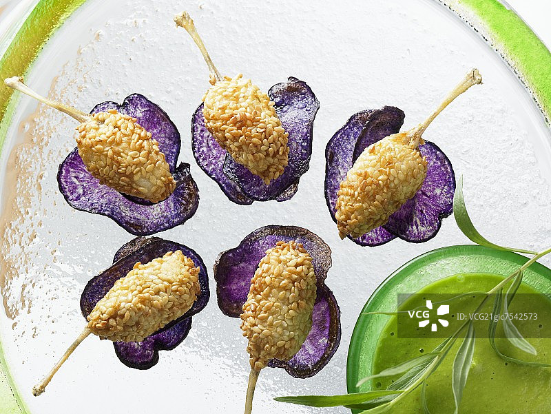 Vitelotte薯片上的香炸芝麻田鸡腿图片素材