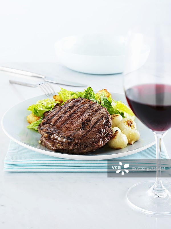 洋葱、罗马生菜和一杯红酒佐肋眼牛排图片素材