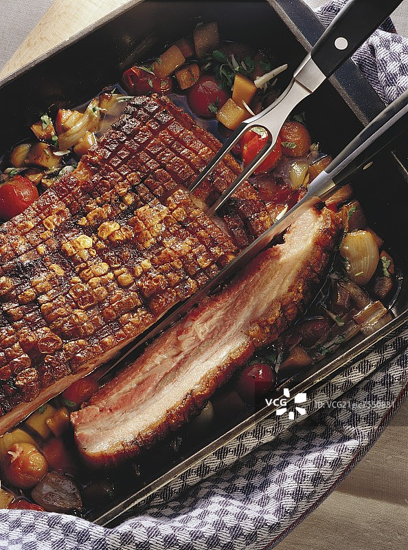 烤盘中的盐渍猪肉，配有肉叉和刀图片素材