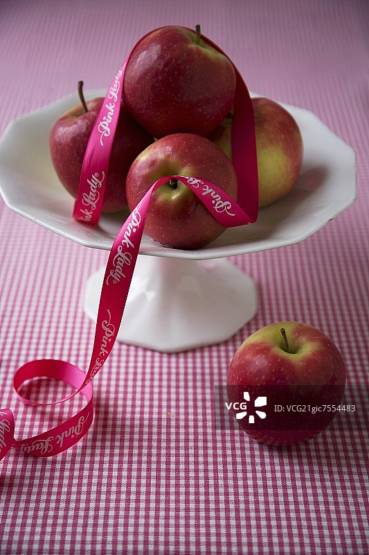 粉红佳人苹果，高脚盘丝带装饰。图片素材