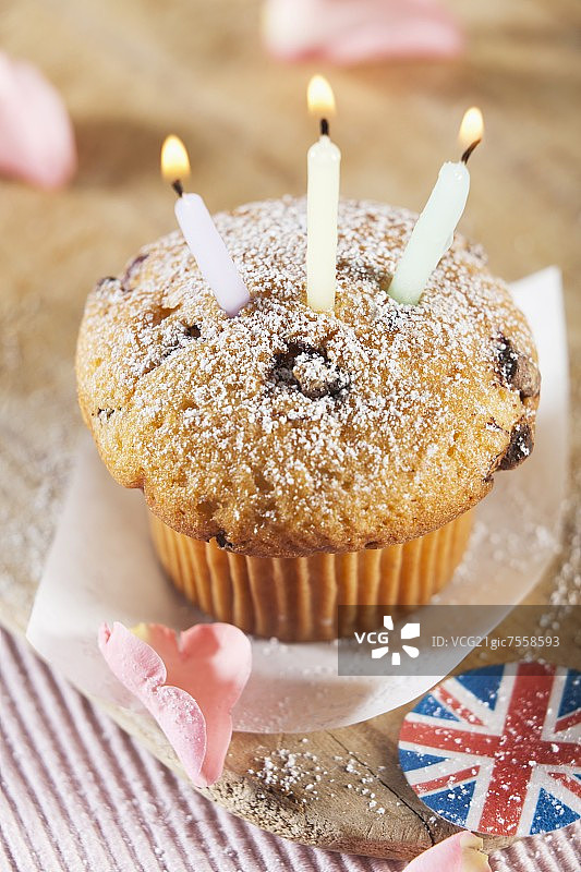 带有英国国旗装饰和玫瑰花瓣的三根蜡烛纸杯蛋糕图片素材