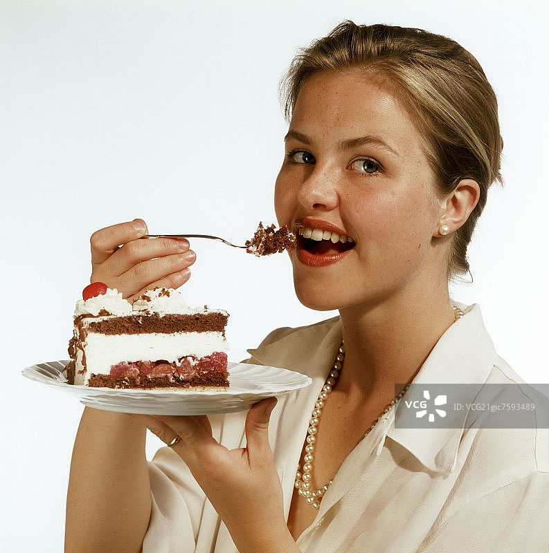 模特正在吃一块黑森林樱桃蛋糕图片素材