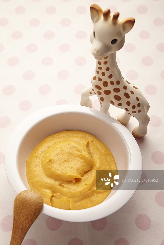 小碟中的胡萝卜泥和玩具长颈鹿图片素材