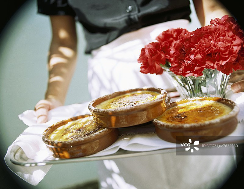 手持托盘，内有加泰罗尼亚奶油和康乃馨图片素材