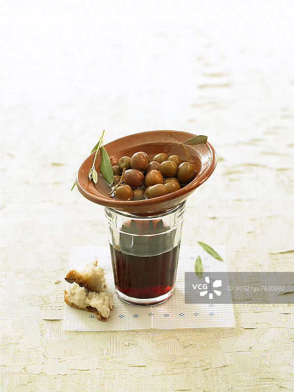 一杯葡萄酒旁的小碗绿橄榄图片素材
