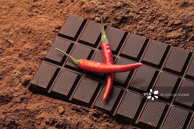 巧克力棒和可可粉上的两个红色辣椒图片素材