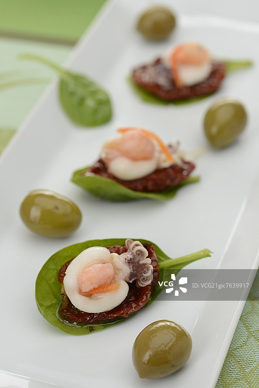 菠菜叶配番茄干、小章鱼和绿橄榄图片素材