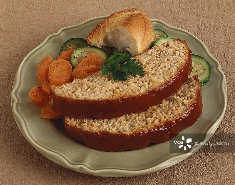 盘子里的两片火鸡肉饼配胡萝卜和西葫芦片图片素材