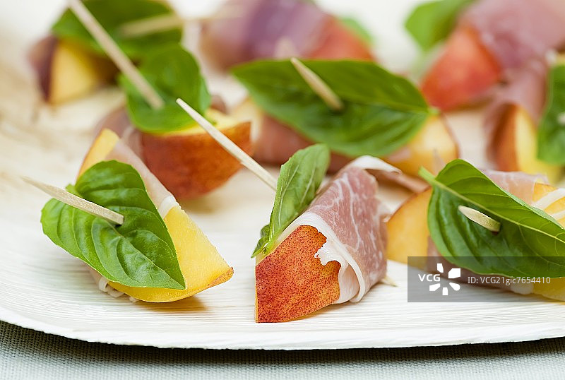 火腿和罗勒包裹的桃子切片与牙签图片素材
