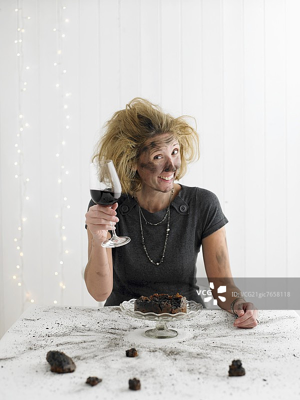 手持红酒坐在爆炸的圣诞布丁前的女人图片素材