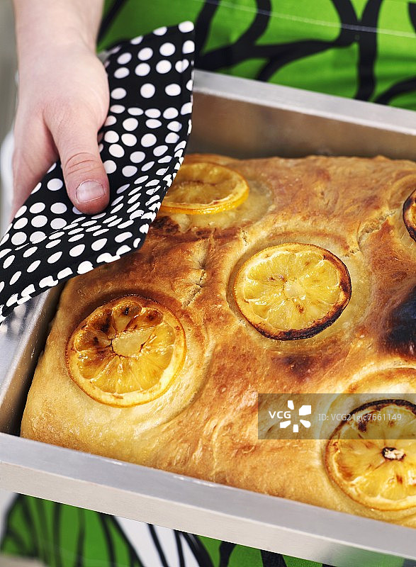 女人在烤盘上拿着柠檬佛卡夏面包图片素材