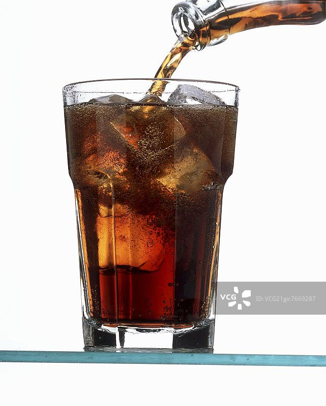 将可乐倒入装有冰块的玻璃杯中（杯子几乎满了）图片素材