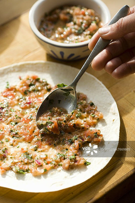 墨西哥卷饼，用番茄莎莎酱涂抹玉米饼图片素材