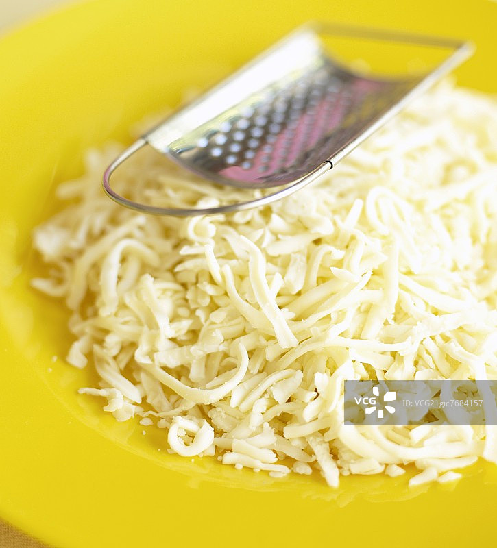 黄色盘子上的磨碎奶酪和磨碎器图片素材