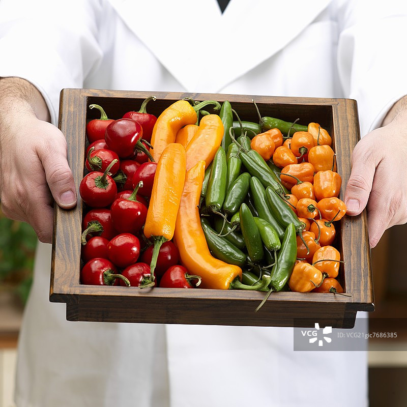 男人端着一盘什锦辣椒图片素材