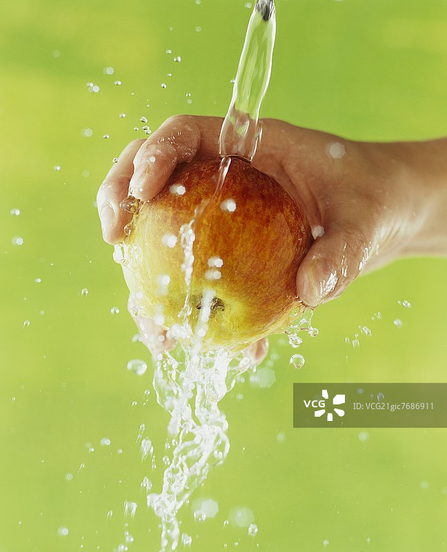 手持在流水下的苹果图片素材