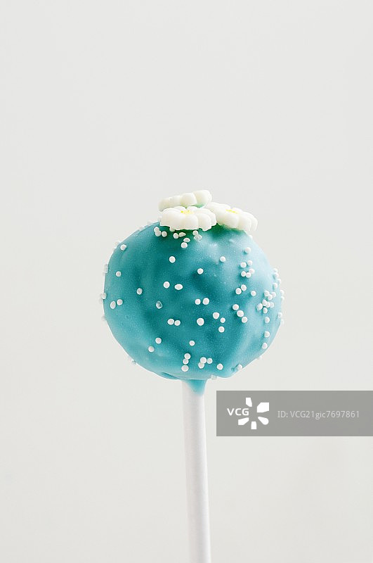 蓝色棒棒糖蛋糕，带有白色糖珠和鲜花图片素材