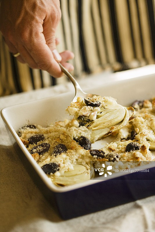 从烤盘中舀出烤茴香配蓝纹奶酪、橄榄和面包屑图片素材