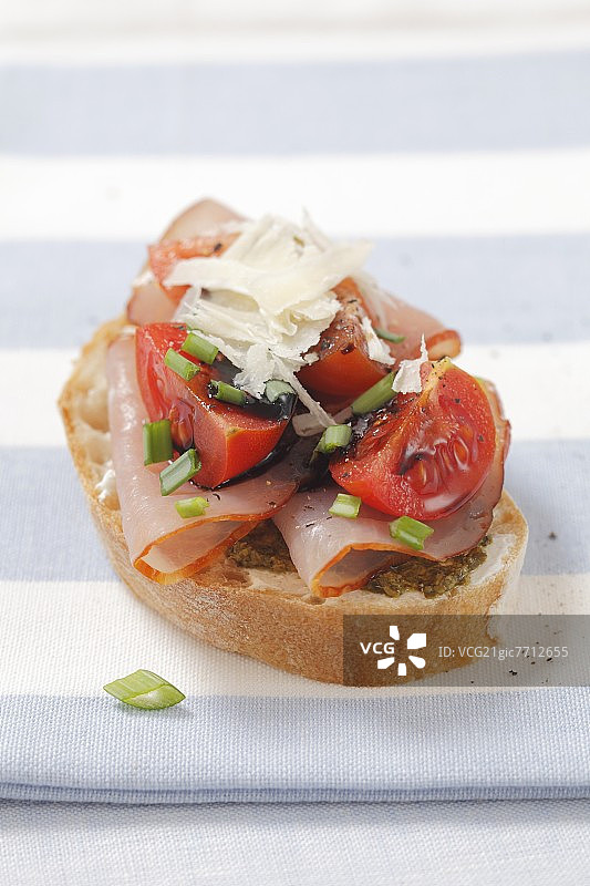 一片法棍面包，上面放着火腿、番茄和帕尔马干酪图片素材