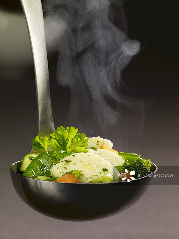 盛满蔬菜炖肉和粗粒小麦饺子的勺子图片素材
