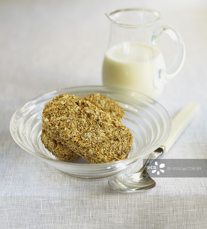 碗里的两块全麦饼干，后面是牛奶图片素材