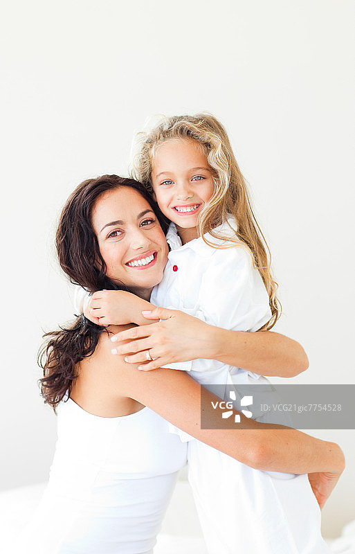 快乐的母女在白色背景的白色床上图片素材