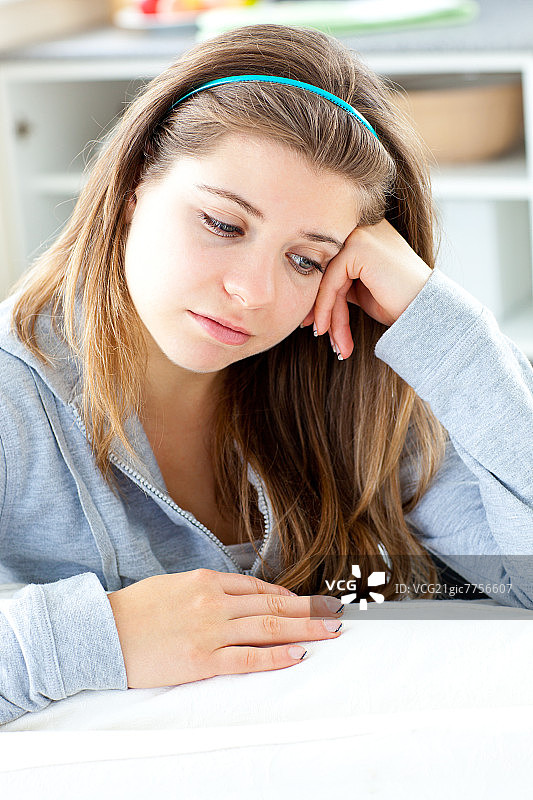 沮丧的年轻女人在家中厨房餐桌旁图片素材