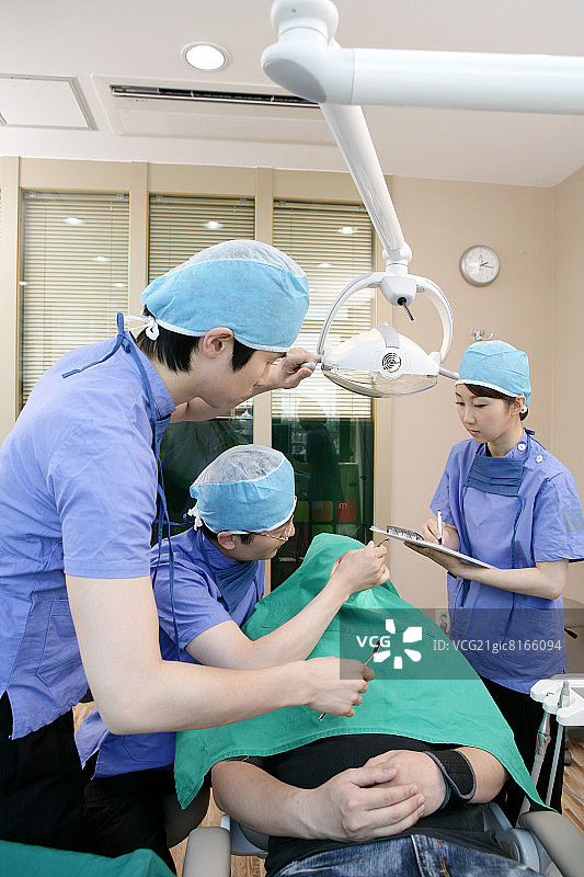 牙医和牙科助手在牙科诊所为病人进行手术图片素材