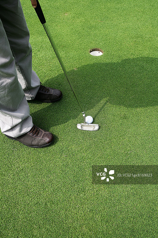 高尔夫球手将球打入高尔夫球洞，低角度拍摄图片素材