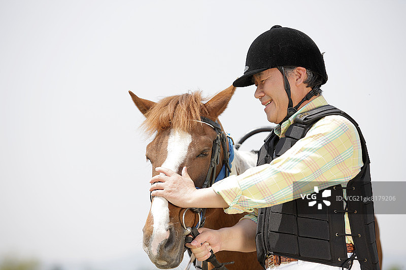 身穿骑行装备，带着马的年长男人图片素材
