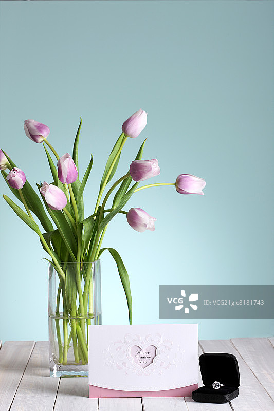 现代玻璃花瓶中的郁金香、卡片和订婚戒指图片素材
